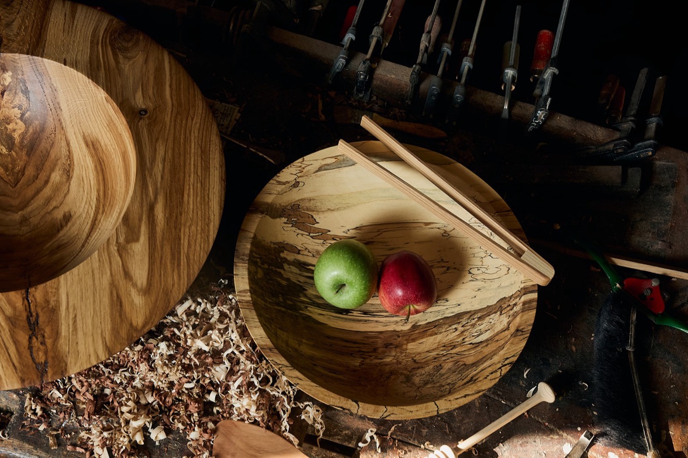 Holzplatte gestockte Buche mit Äpfeln vor der Werkzeugwand