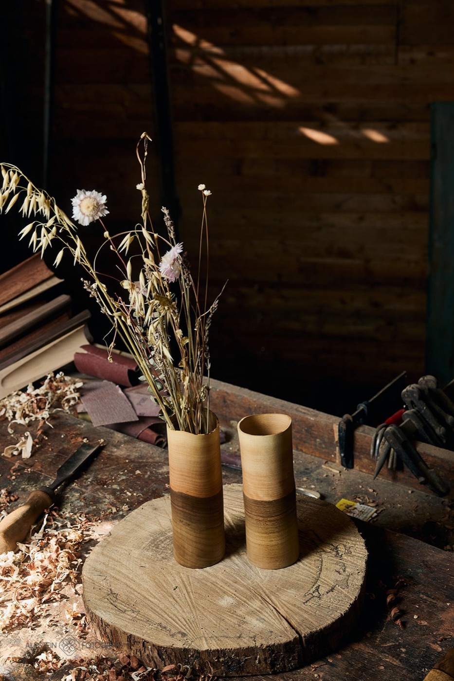 Zwei Holzvasen aus Nussbaum mit Trockenblumen auf einer Eichenscheibe