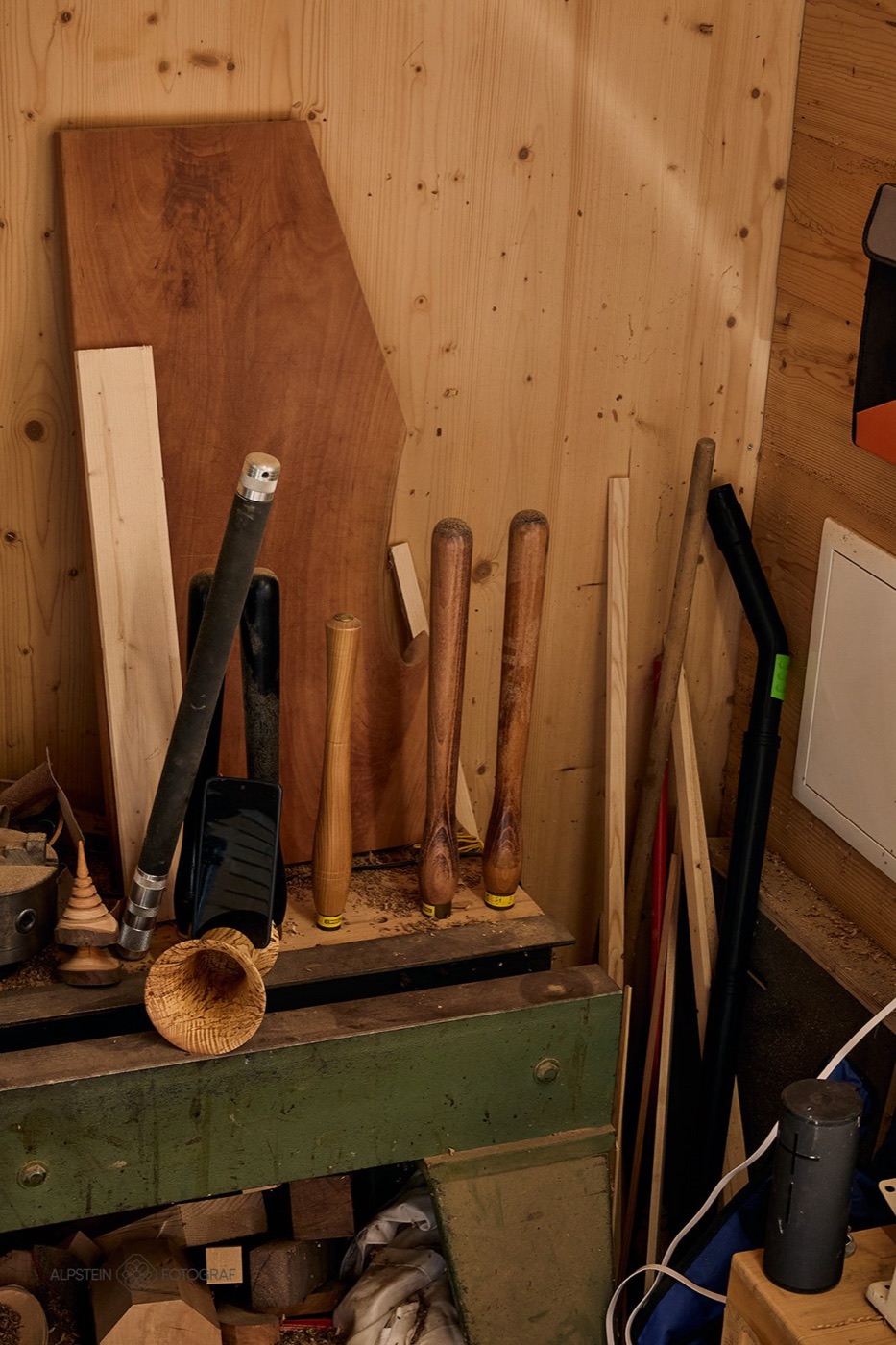 Gedrechselte Werkzeuggriffe, Bretter und ein Holztrichter in der Werkstattecke