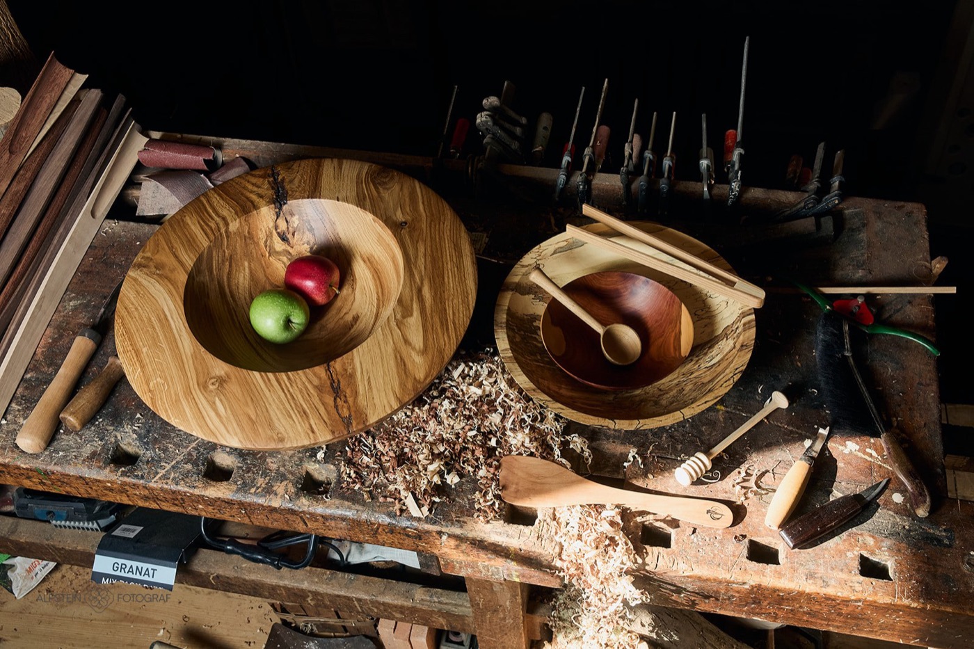Werkbank in der Holzwerkstatt mit Schalen, Holzlöffeln und Drechselwerkzeug